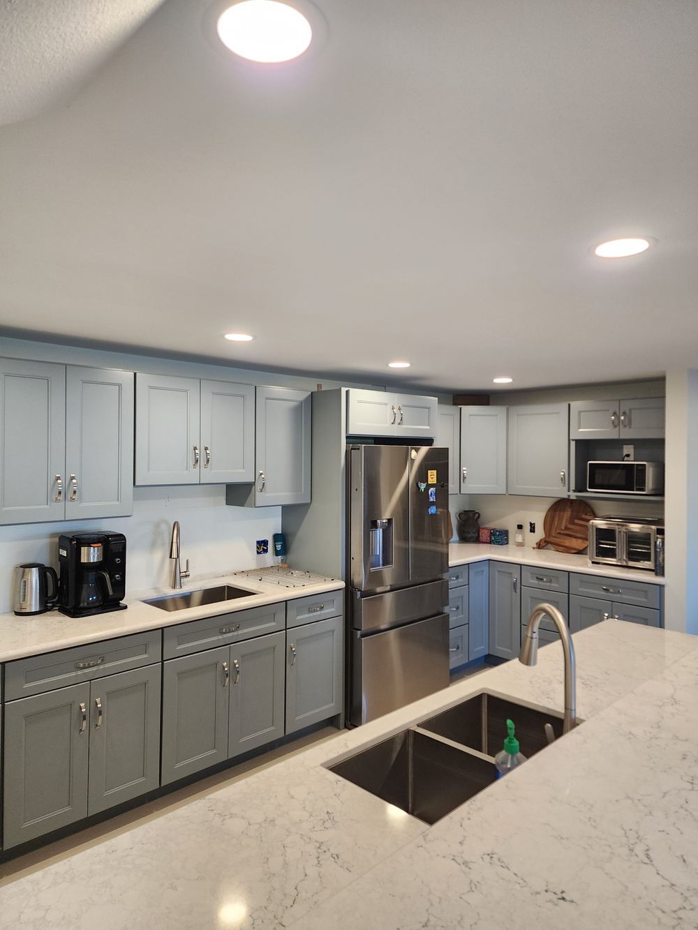 Remodeled kitchen with gray cabinets and stone counters